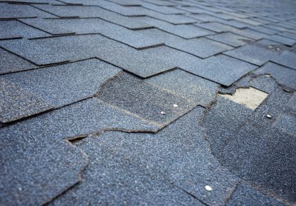 Сlose up view of bitumen shingles roof damage that needs repair.