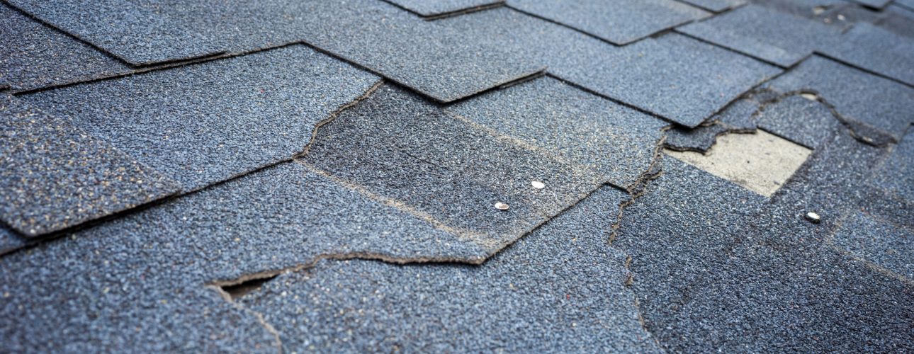 Сlose up view of bitumen shingles roof damage that needs repair.